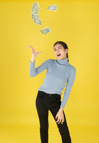 Young woman standing against yellow background