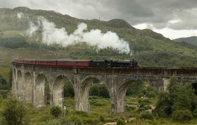 Arch bridge over mountains against sky