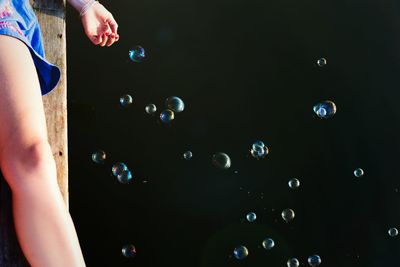 Woman lying down on pier by bubbles at lake