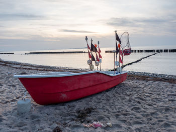 Red fishing boat lying on beach of ruegen at dranske village. evening windless mood at baltic  shore
