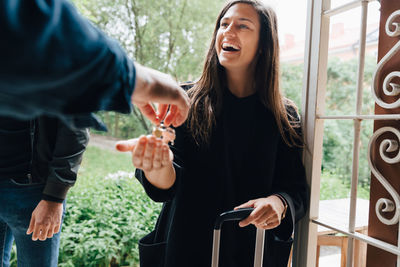 Smiling woman receiving house keys from owner while standing at doorway