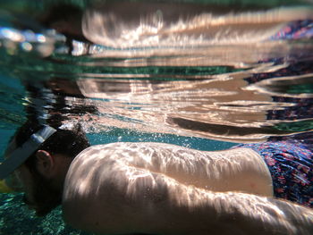 Close-up of young man swimming underwater 