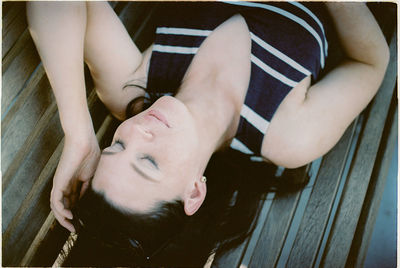 High angle view of young woman lying on bench