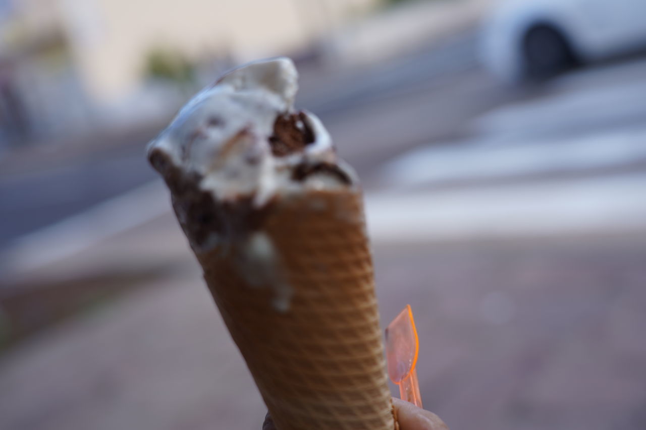 CLOSE-UP OF A HAND HOLDING ICE CREAM