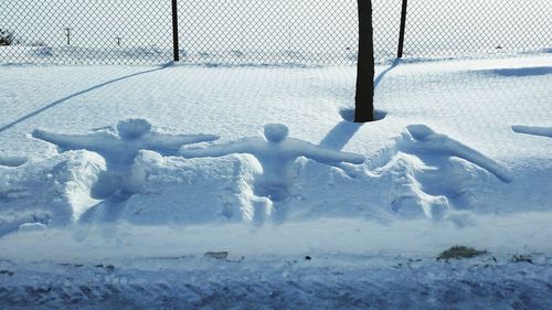 Human prints on snow covered land against fence