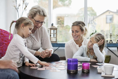 Three generation females playing card puzzle game at home