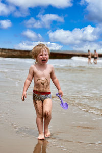 Rear view of shirtless boy playing at beach