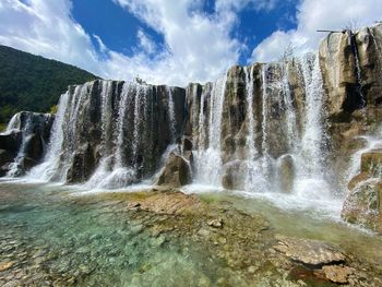 Scenic view of waterfall against sky