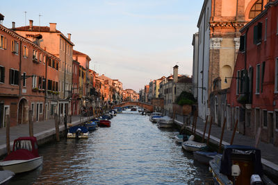 Canal amidst buildings in city against sky