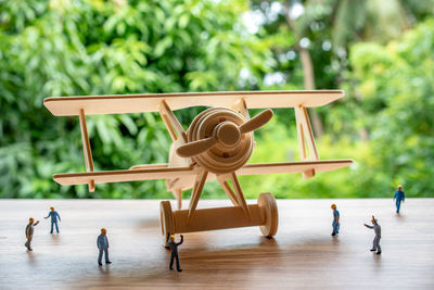 Close-up of figurines and model airplane on table with trees in background