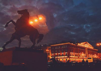 Statue in illuminated city against sky at night