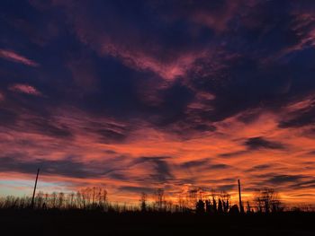 Silhouette landscape against dramatic sky during sunset