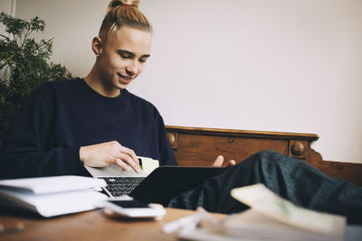 Teenage boy using laptop while sitting on sofa at home