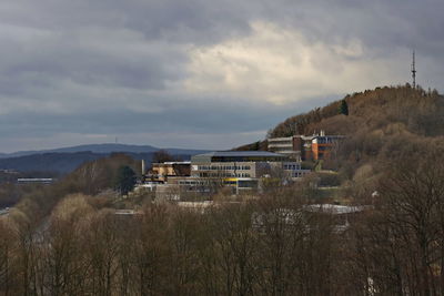 Houses on field by buildings against sky