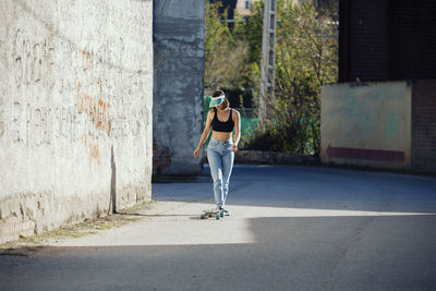 Full length of young woman skateboarding on street