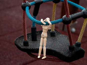 Close-up of wooden figurine hanging on rope