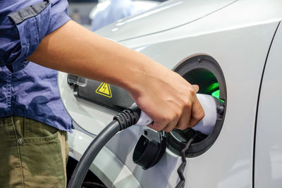 Midsection of man refueling car