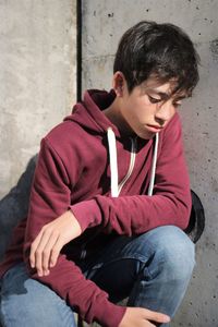 Thoughtful boy crouching against wall