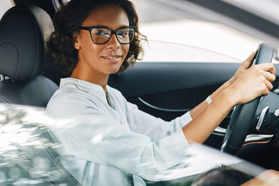 Portrait of smiling young woman driving car