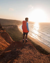 Rear view of man walking on beach against sky