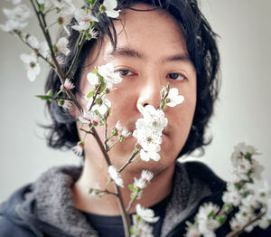 Portrait of young asian man framed by cherry plum blossoms.