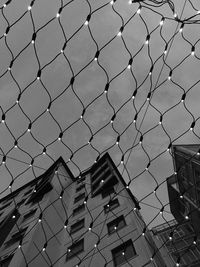 Low angle view of chainlink fence against building