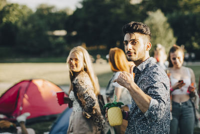 Portrait of smiling man gesturing while enjoying with friends at concert