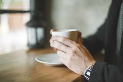 Midsection of man holding coffee cup