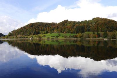 Scenic view of calm lake surrounded by mountain against sky