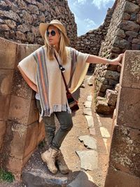 Portrait of young woman standing against wall