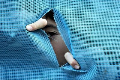 Close-up portrait of boy peeking through textile