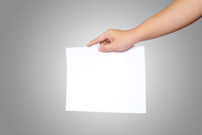 Midsection of person holding paper against white background