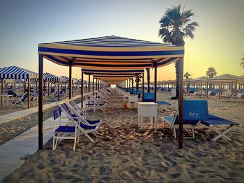 Deck chairs on beach against sky