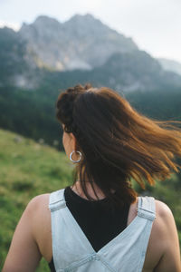 Side view of young woman looking away against mountain