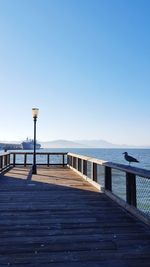 Pier over sea against clear blue sky