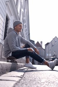 Surface level view of man sitting on skateboard in city