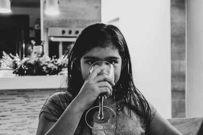 Portrait of girl drinking juice while sitting at home