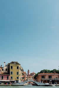 River and buildings in city against clear sky