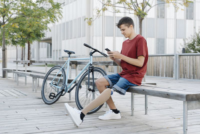 Man with disability using smartphone near bicycle