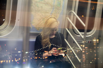 YOUNG WOMAN LOOKING THROUGH WINDOW AT ILLUMINATED GLASS