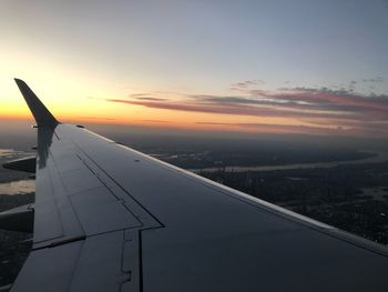Airplane wing against sky during sunset