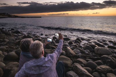 Couple taking selfie from mobile phones at beach during sunset