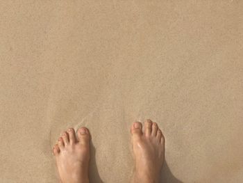 Low section of person standing on sand