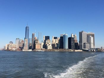 One world trade center by east river against clear blue sky at manhattan