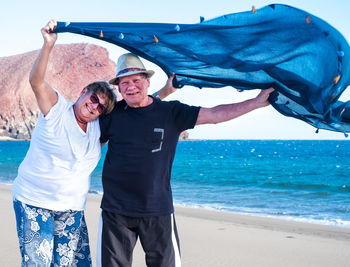 Portrait of senior couple holding scarf at beach