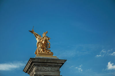 Low angle view of angel statue against blue sky