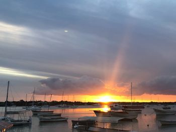 Boats moored in harbor at sunset