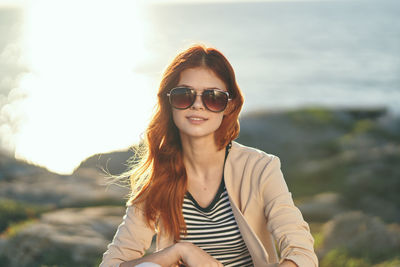 Portrait of young woman wearing sunglasses against sky