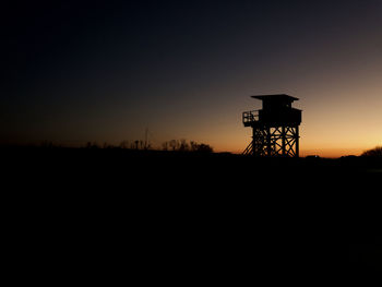 Silhouette built structure on field against sky during sunset