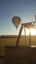 Hot air balloon flying over land against sky during sunset